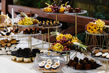 Many cakes standing among the candy bar. Sweet table. Banquet table. Holiday food and sweet festive table.