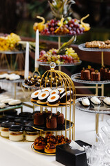 Many cakes standing among the candy bar. Sweet table. Banquet table. Holiday food and sweet festive table.