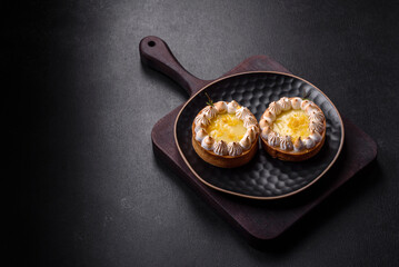 Delicious fruity sweet tart with lemon flavor and cream on a black plate