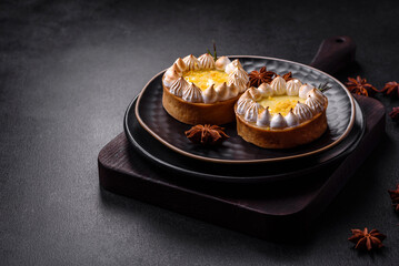 Delicious fruity sweet tart with lemon flavor and cream on a black plate