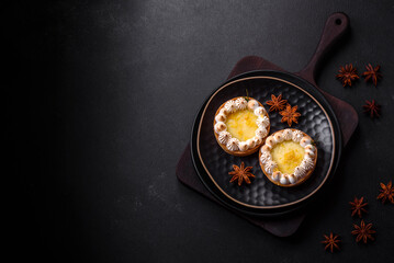 Delicious fruity sweet tart with lemon flavor and cream on a black plate