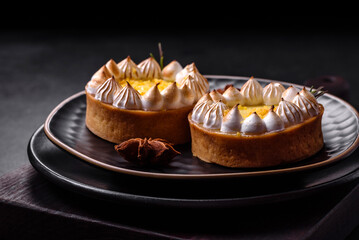 Delicious fruity sweet tart with lemon flavor and cream on a black plate