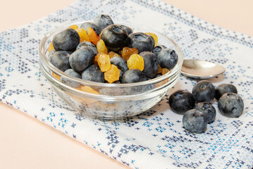 In a small glass bowl, fresh blueberries with raisins.