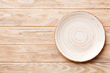 Top view of empty colorful plate on wooden background. Empty space for your design