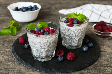 Healthy breakfast or morning with chia seeds vanilla pudding raspberry and blueberry berries on table background, vegetarian food, diet and health concept. Chia pudding with raspberry and blueberry