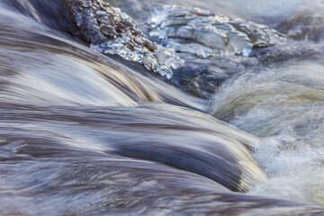 Water stream waves with golden light, evening light reflecting on water