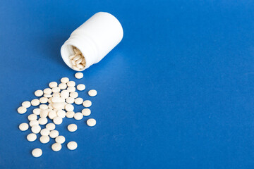 Medicine bottle and white pills spilled on a light background. Medicines and prescription pills flat lay background. White medical pills and tablets spilling out of a drug bottle