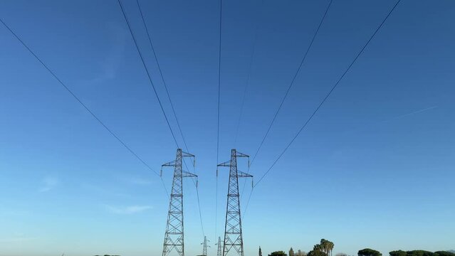 Electricity power lines in the field, high voltage tower pylons transmitting electricity with high tension, power stations and substations working without interruption to supply cities and regions