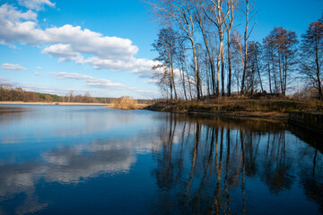 Ein kleiner blauer See mit einer Spiegelung der umherstehenden Bäumen und Wolken