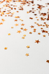 Shiny golden stars confetti scattered on a blue pastel background. Selective focus.