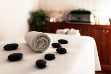 Fototapeta na wymiar Towel and lava stones on massage table in spa salon