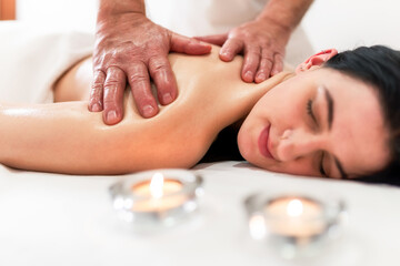 Obraz na płótnie Canvas Masseur massaging back and shoulder blades of young woman lying on massage table on white background. Concept of massage spa treatments