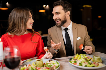 smiling young couple in festive attire talking during celebration on valentines day