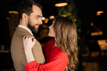 happy man and woman in festive attire hugging while looking at each other on valentines day