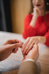 cropped view of man holding engagement ring and hand of girlfriend on valentines day