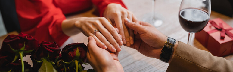 cropped view of woman with engagement ring on finger holding hands with man on valentines day, banner - obrazy, fototapety, plakaty