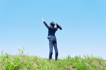 屋外でガッツポーズするビジネスマンの後ろ姿