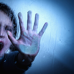 Young girl with a raised hand showing STOP gesture behind wet glass. Copy space.
