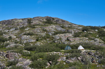 Fototapeta na wymiar Two tourist tents on the green slope of the mountain