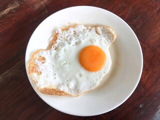 Abstract photo of fried egg in sunny-side-up eggs server in white plate on wooden table 