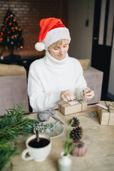 Woman wrapping christmas presents with eco materials at home