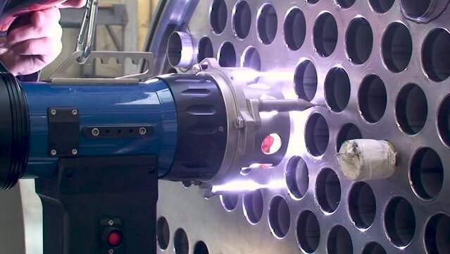 Welding shell and tube in tube heat exchanger. Welding head equipment. Automatic welding machine. Skilled welder. Side view, Static shot.