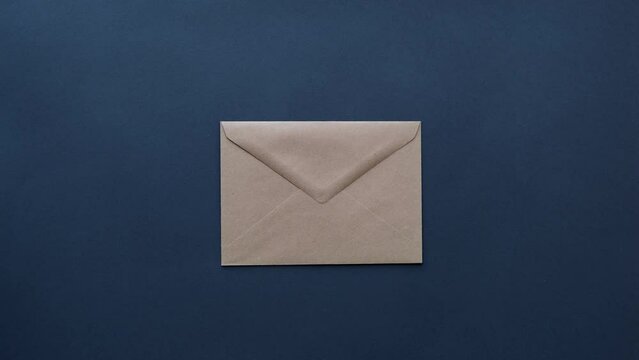 Woman's hand puts a craft mail envelope on a dark table top view