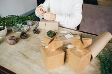 Woman wrapping christmas presents with eco materials at home