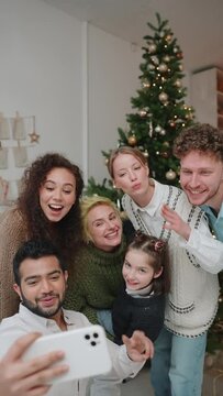 Cheerful international family celebrates Christmas and take selfie photo at home indoors