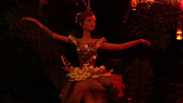 A figurine of a ballerina hangs on a Christmas tree with a garland. Christmas decoration