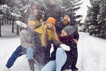 Joyful happy young friends have fun and enjoy winter day during walk in forest. Portrait of funny...