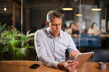 Fototapeta premium Portrait of businessman in office. Man using digital tablet. Businessman having video call.