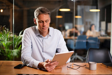 Obraz premium Portrait of businessman in office. Man using digital tablet. Businessman having video call.