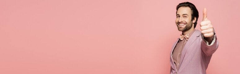 Positive host of event showing thumb up at camera isolated on pink, banner