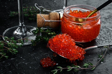 A spoonful of red caviar. Luxury food. On a black background. Free space for text.