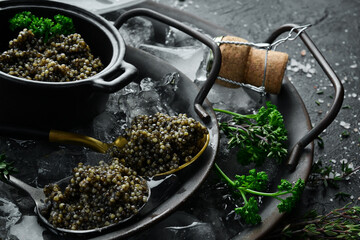 Black Sturgeon caviar on ice with parsley and a spoon. On concrete texture background. - obrazy, fototapety, plakaty