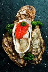 Open oysters with red caviar, on ice. On a stone background. Top view. Macro photo.