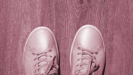 Viva magenta banner of light pink sneakers close-up on a wooden background. Top view