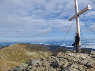 Man standing at the summit cross of Zirbitzkogel, Seetal Alps in Murtal, Styria, Austria, Europe....