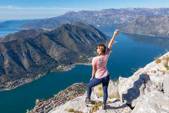 Woman with scenic view from Pestingrad (Derinski Vrh) of Kotor bay in sunny summer, Adriatic Mediterranean Sea, Montenegro, Balkan, Europe. Fjord winding along coastal towns. Lovcen, Orjen mountains