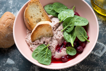 Liver pate served with cranberry sauce, fresh spinach and ciabatta in a roseate bowl, middle close-up