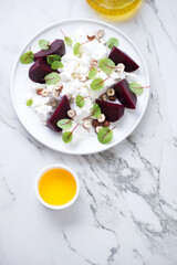 Fototapeta na wymiar Plate with beetroot and feta cheese salad on a white marble background, vertical shot with copy space, flat lay