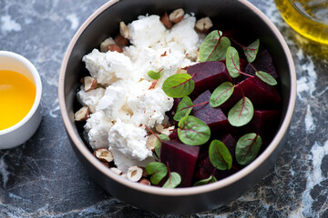 Bowl of salad with feta cheese, beetroot, hazelnuts and fresh beetroot leaves, middle close-up, selective focus