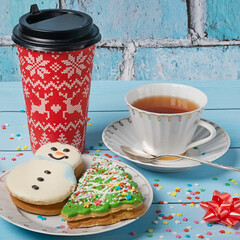 Gingerbread in the form of a Christmas tree and a snowman. A cup of tea and a glass of coffee on a blue background. New year and christmas concept