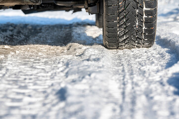 Winterreifen eines Autos auf schneebedeckter Fahrbahn im Detail