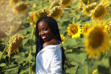 portrait of a happy young african woman in a field with sunflowers	