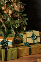 Fototapeta na wymiar beautiful New Year's gifts in boxes in gold paper with green ribbons under the Christmas tree