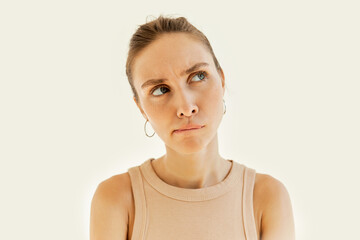 Head shot of pretty puzzled perplexed female frowning curving her lips with hmm facial expression,...
