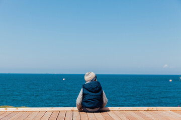 little boy looks at the blue sea on the beach