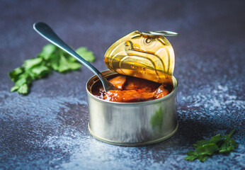 Canned octopus with american sauce open on a dark blue table with a fork and parsley. Ready for eat. 